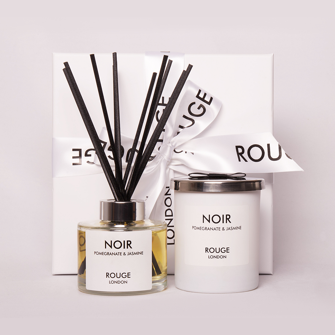 A luxury candle and diffuser set, with the candle labeled 'NOIR' and the diffuser labeled 'ROUGE LONDON', displayed on a pink surface.